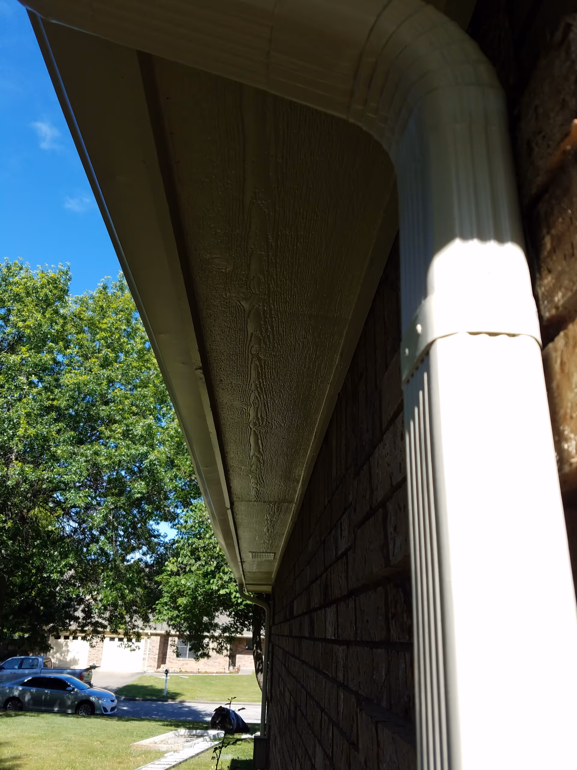 Side view of a brick facility with a white gutter and blue sky.