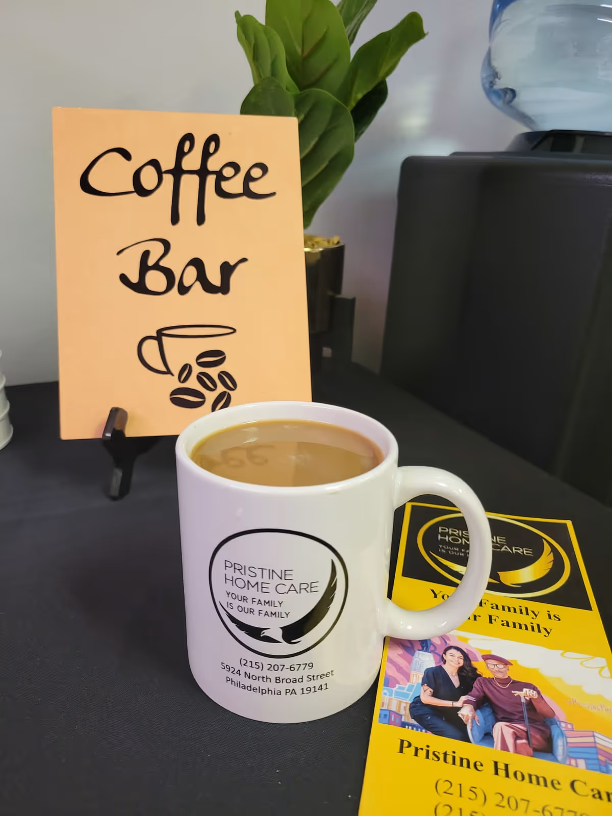 Coffee bar setup with mug and Pristine Home Care sign in a facility.