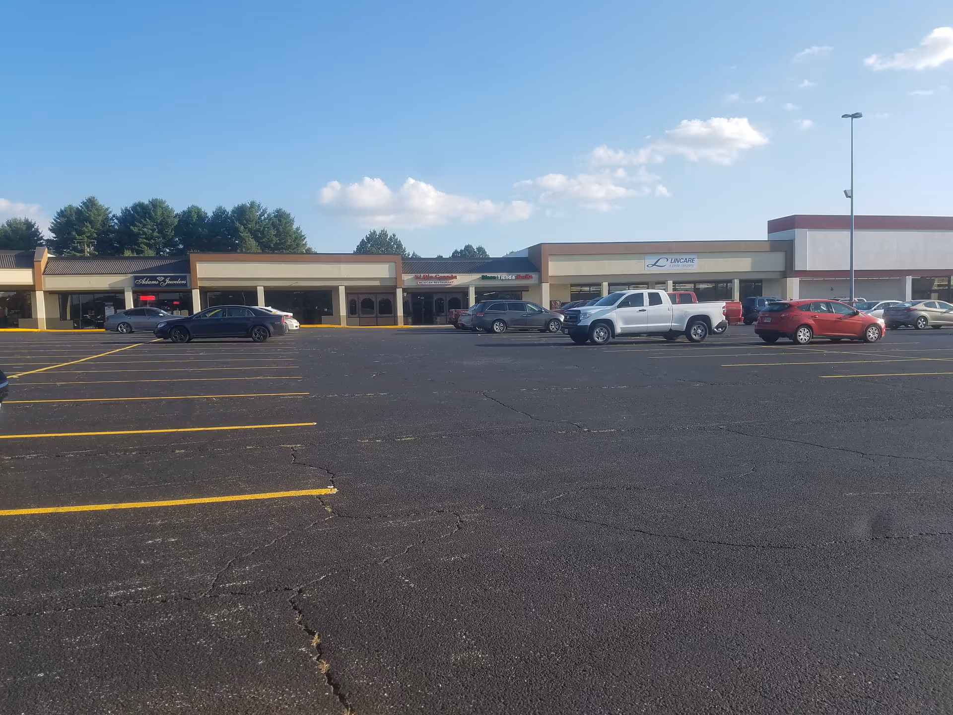 Exterior view of a strip mall with a LinCare sign and parked cars in front.