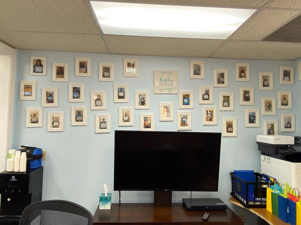 Interior office area with a blue wall gallery of framed photos and a large monitor.