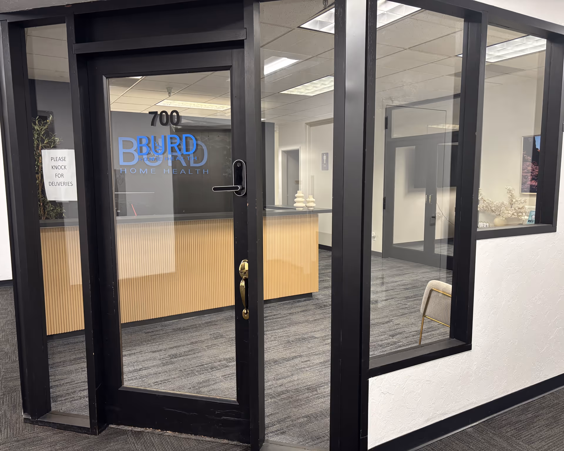 Glass door entrance with Burd Home Health signage and a reception desk inside.
