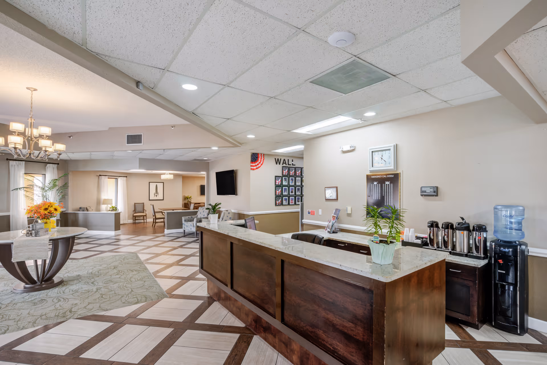 Reception desk in a spacious senior living facility lobby with seating and coffee station.