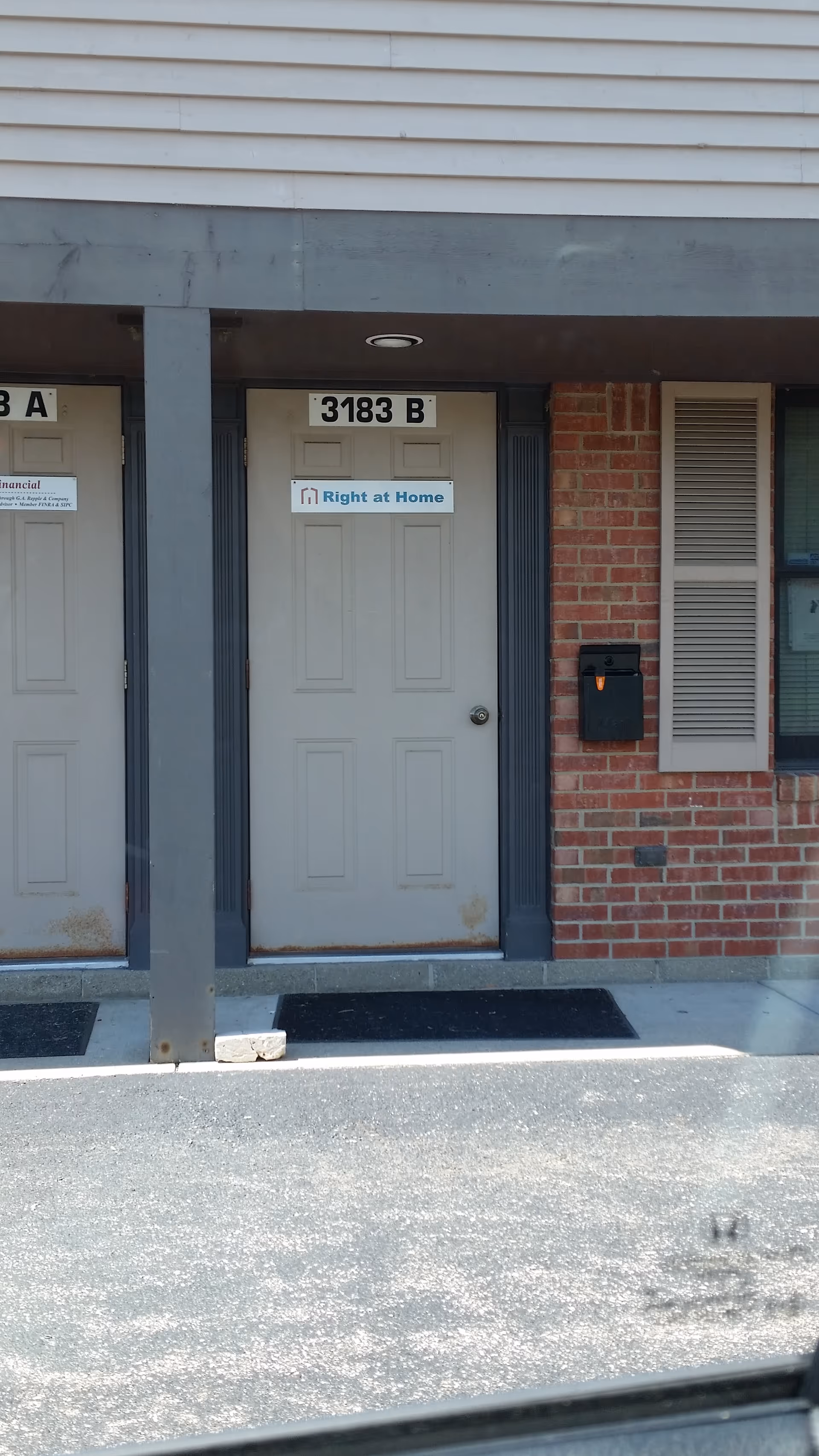 Front exterior of a building with gray doors, brick wall, and a Right at Home sign.