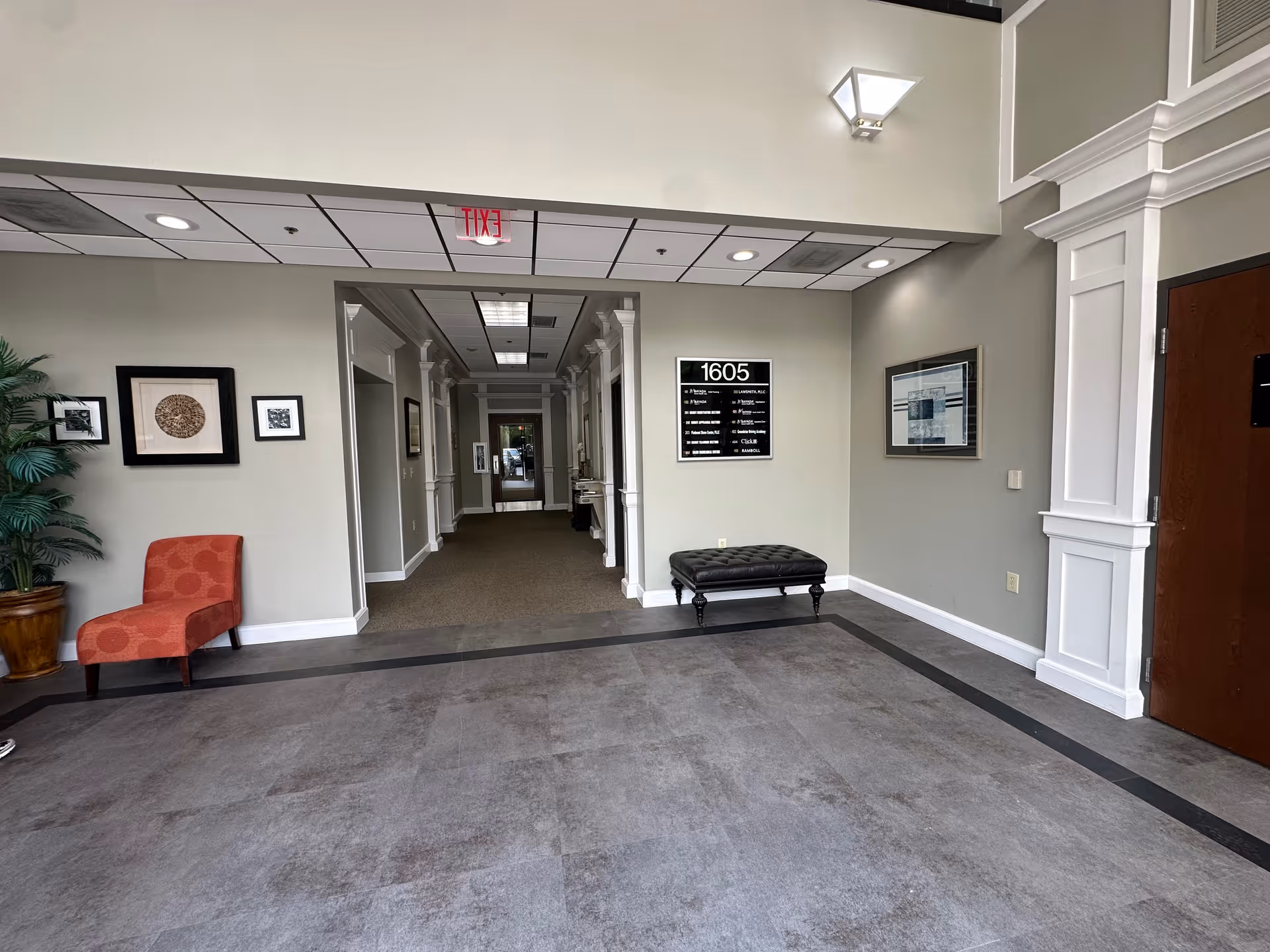 Interior lobby with seating, wall art, a plant, and a long hallway.