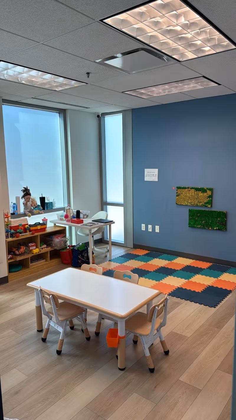 Colorful children's play area with a small table, chairs, toys, and foam mats.
