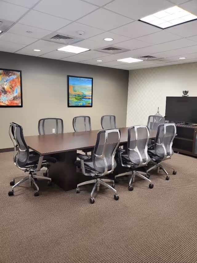 Long conference table with ergonomic chairs in a meeting room.