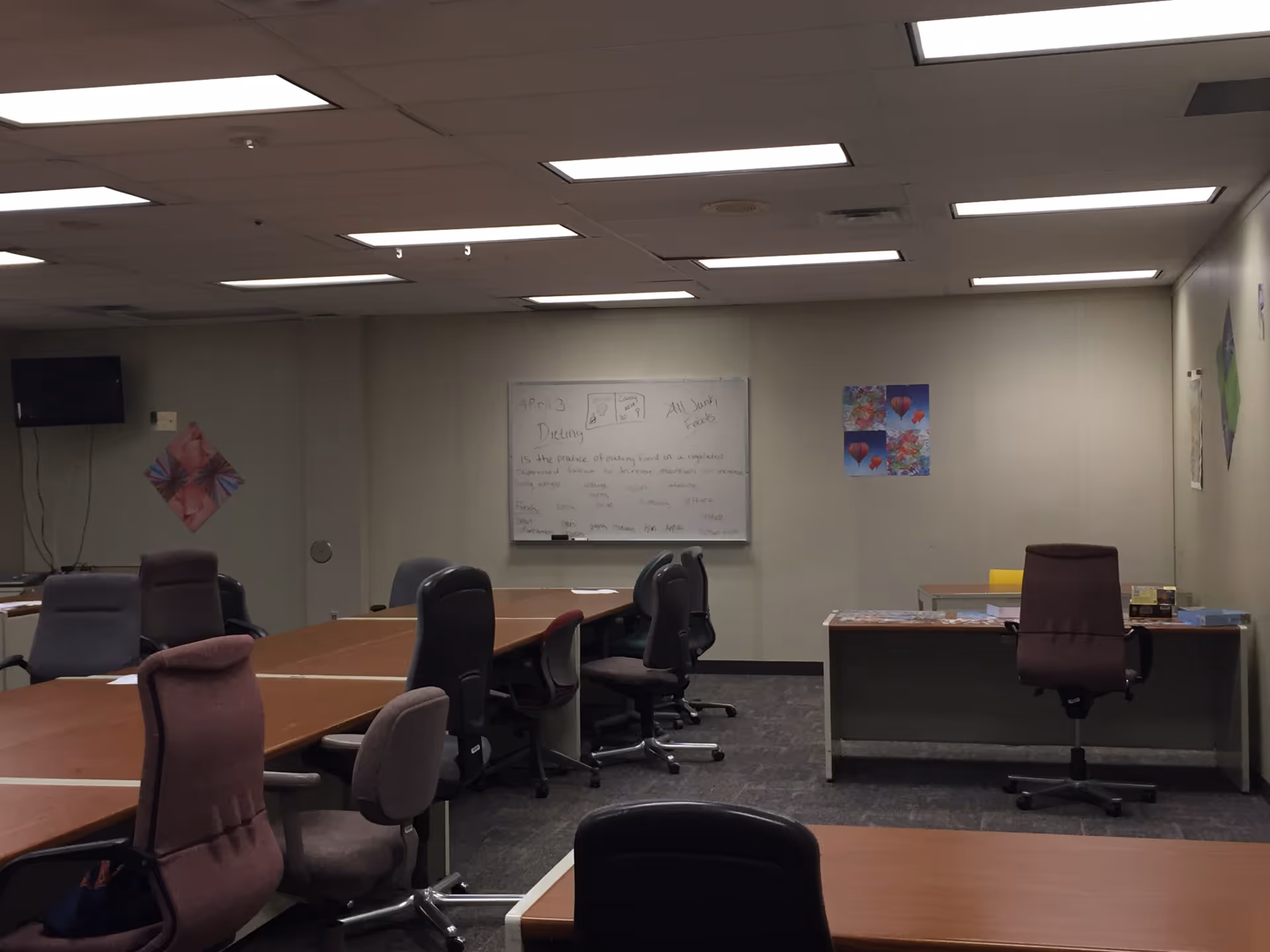 Interior conference room with long tables, chairs, and a whiteboard.