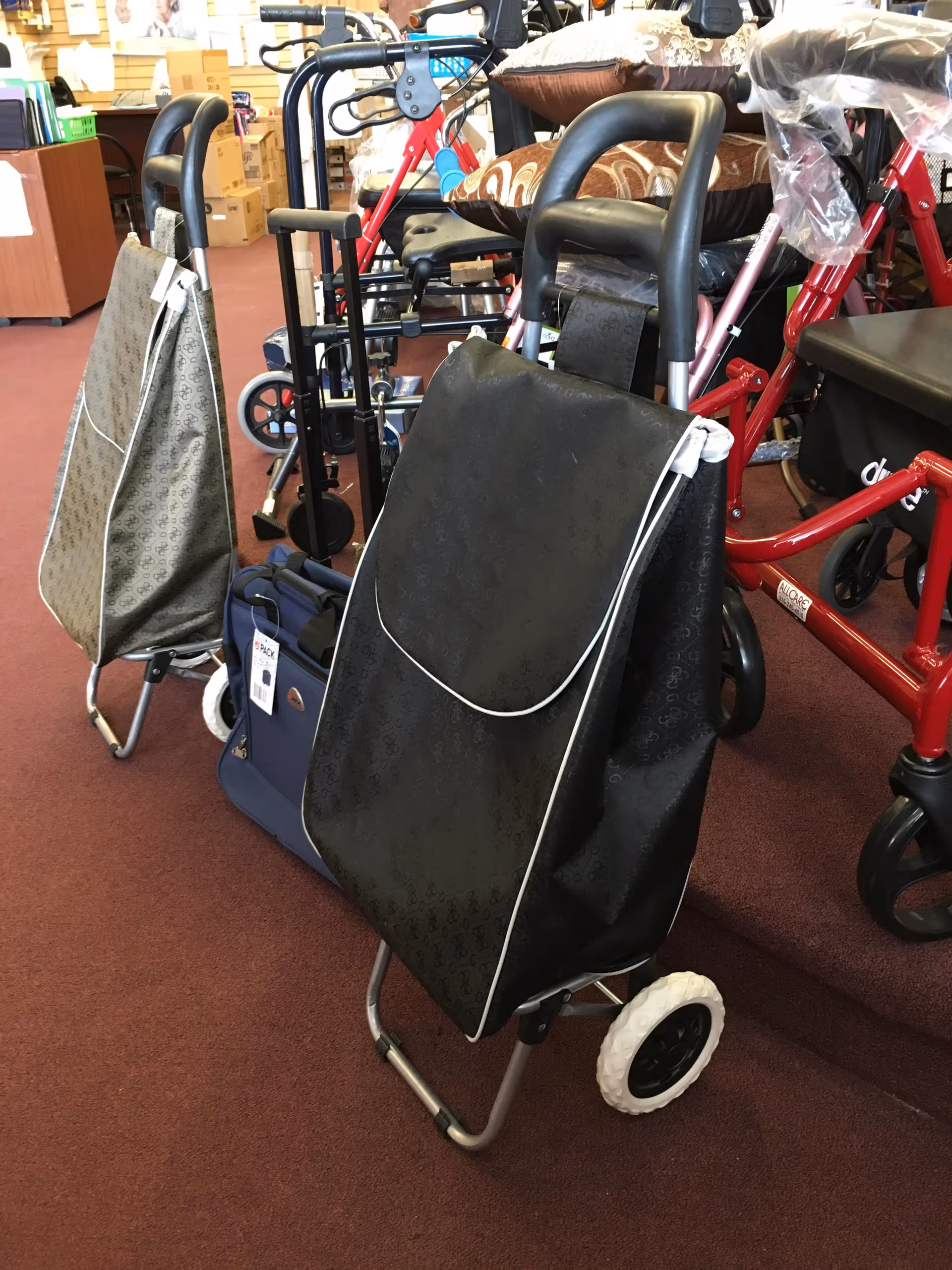 Indoor showroom with mobility scooters, walkers, and bags on display.