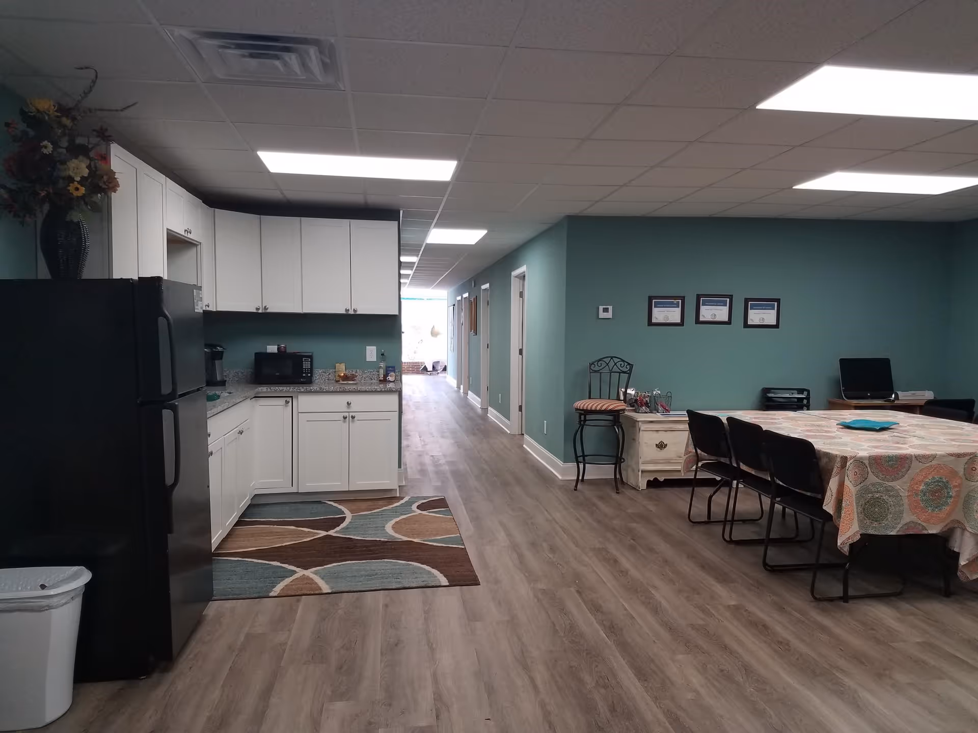 Long hallway with a kitchenette on the left and a dining table on the right.