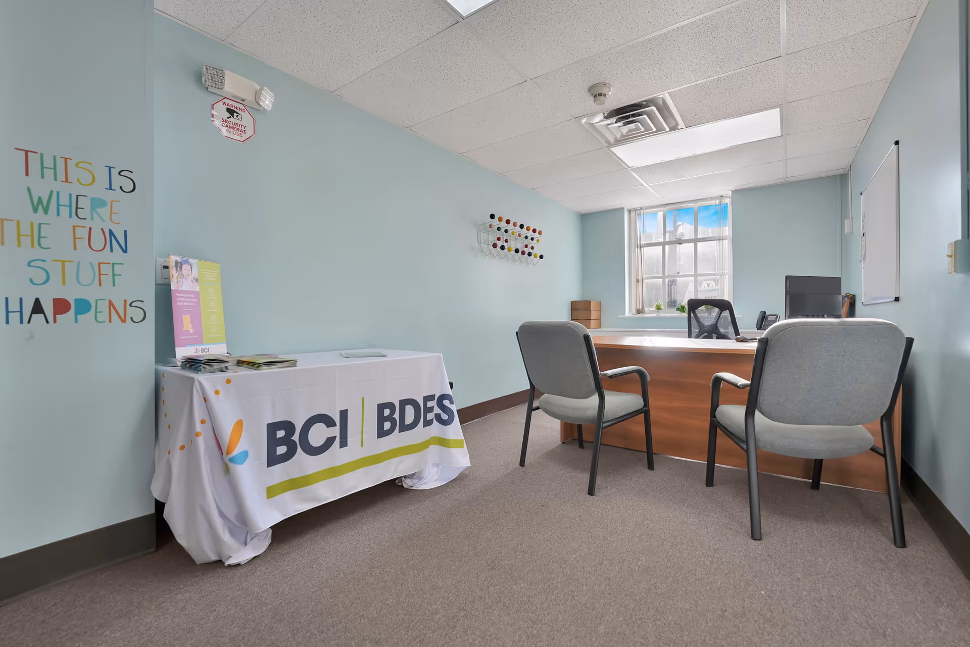 Interior office space with a BCI bannered table, chairs, and a window.