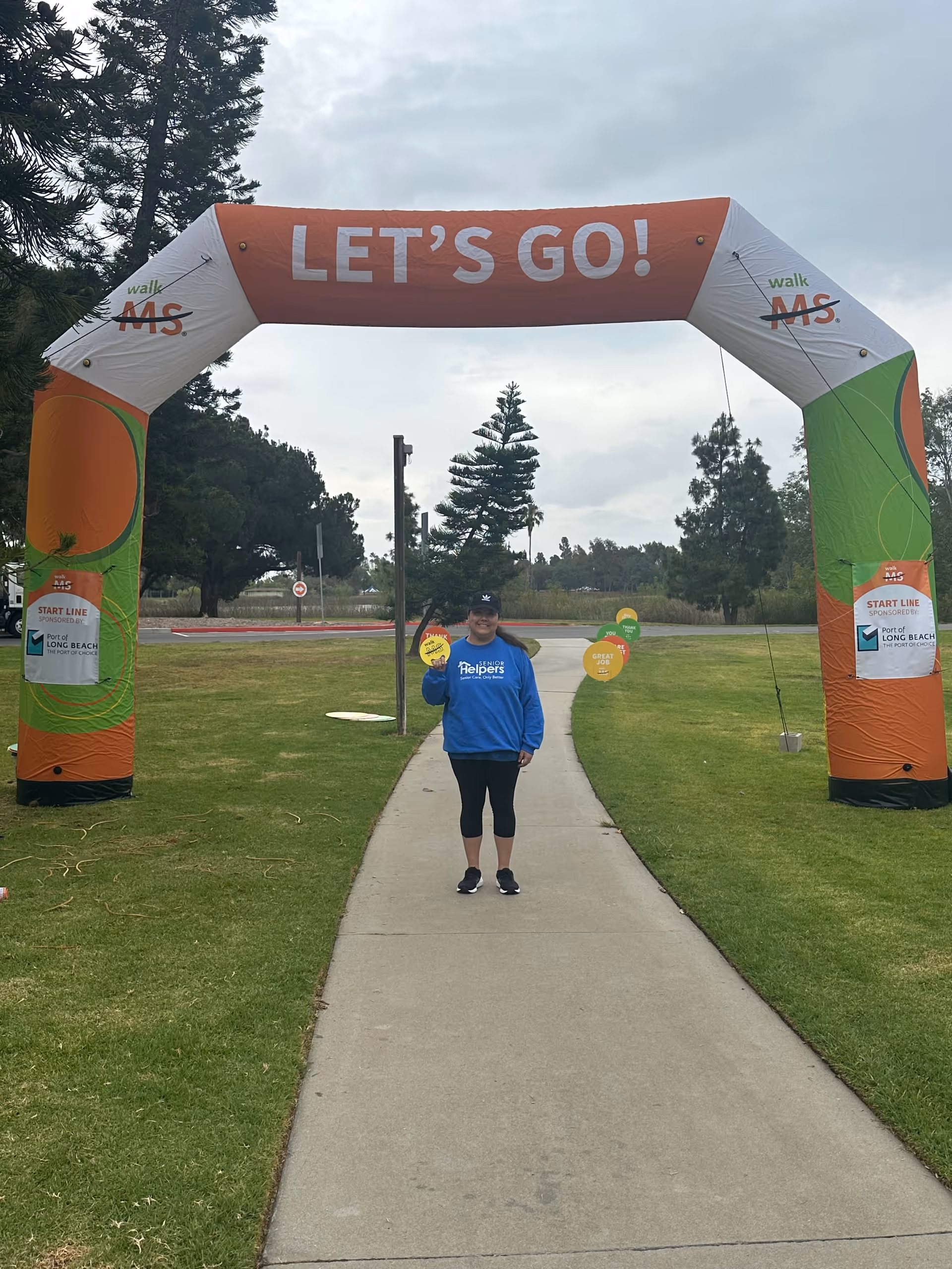 A person in a blue Senior Helpers shirt stands beneath a large LET'S GO arch.