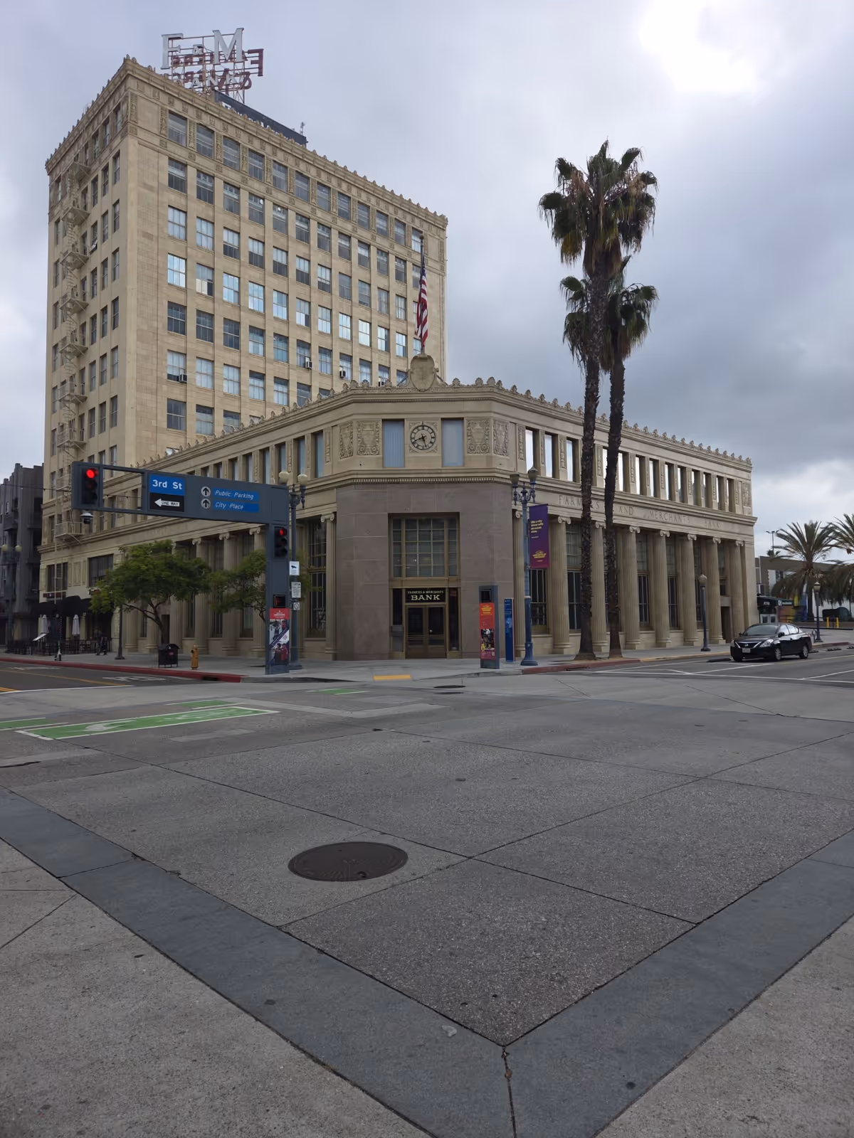 Corner street view of a large historic bank building with palm trees