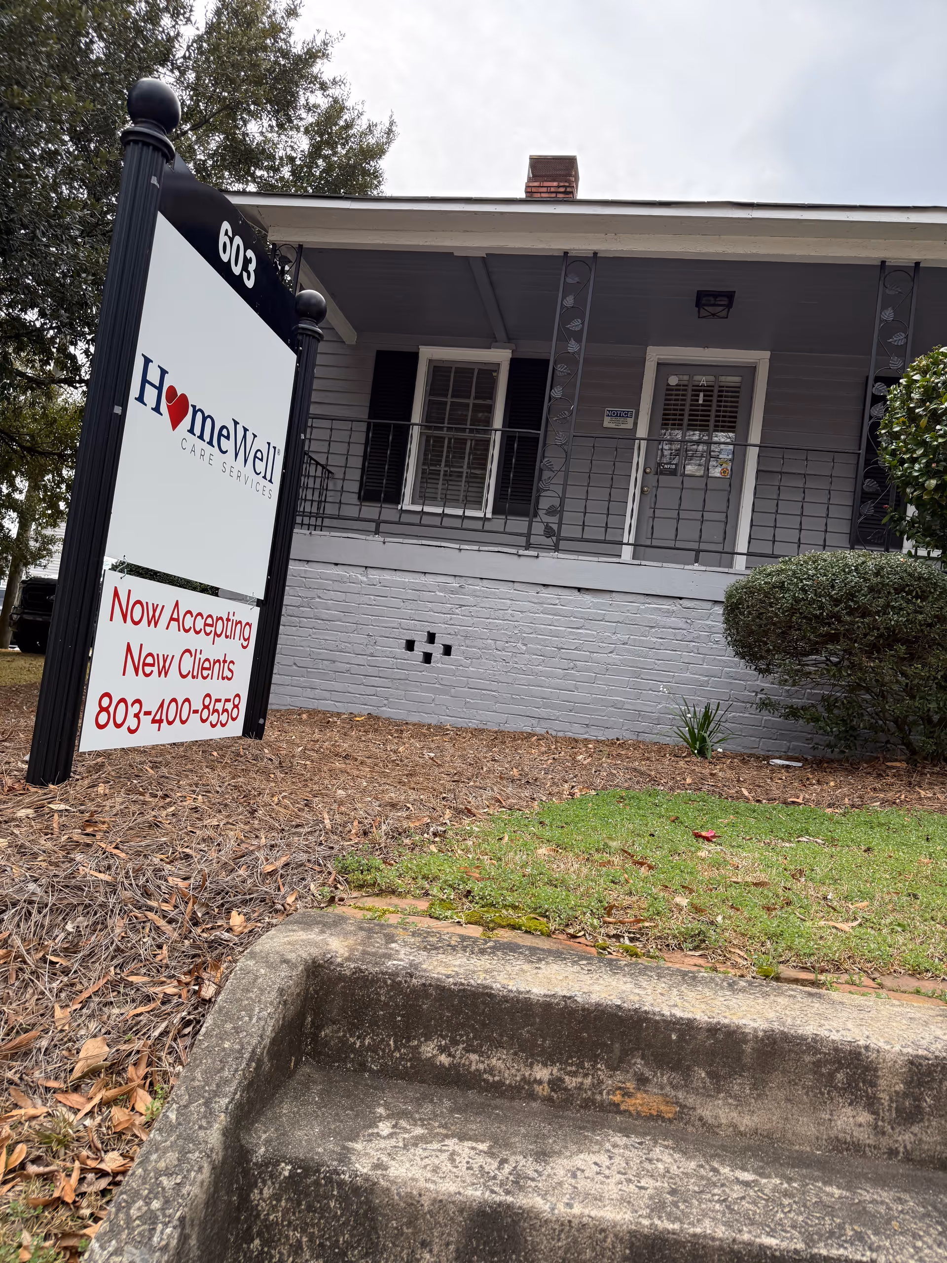 Exterior view of a HomeWell Care Services building with a sign and porch.