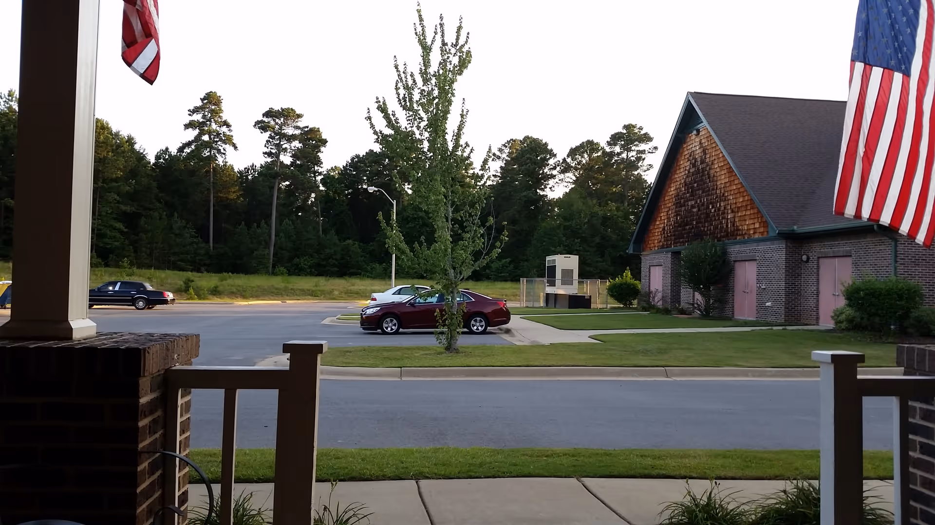 Front view of Life Touch Hospice building with American flags, a parking lot, and surrounding greenery.