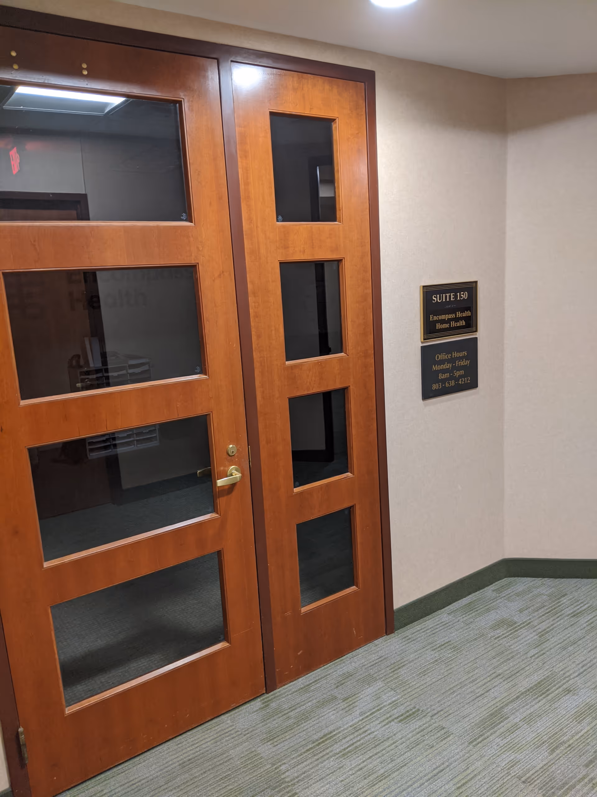 Wooden double doors with glass panels in a hallway, suite sign on the wall.