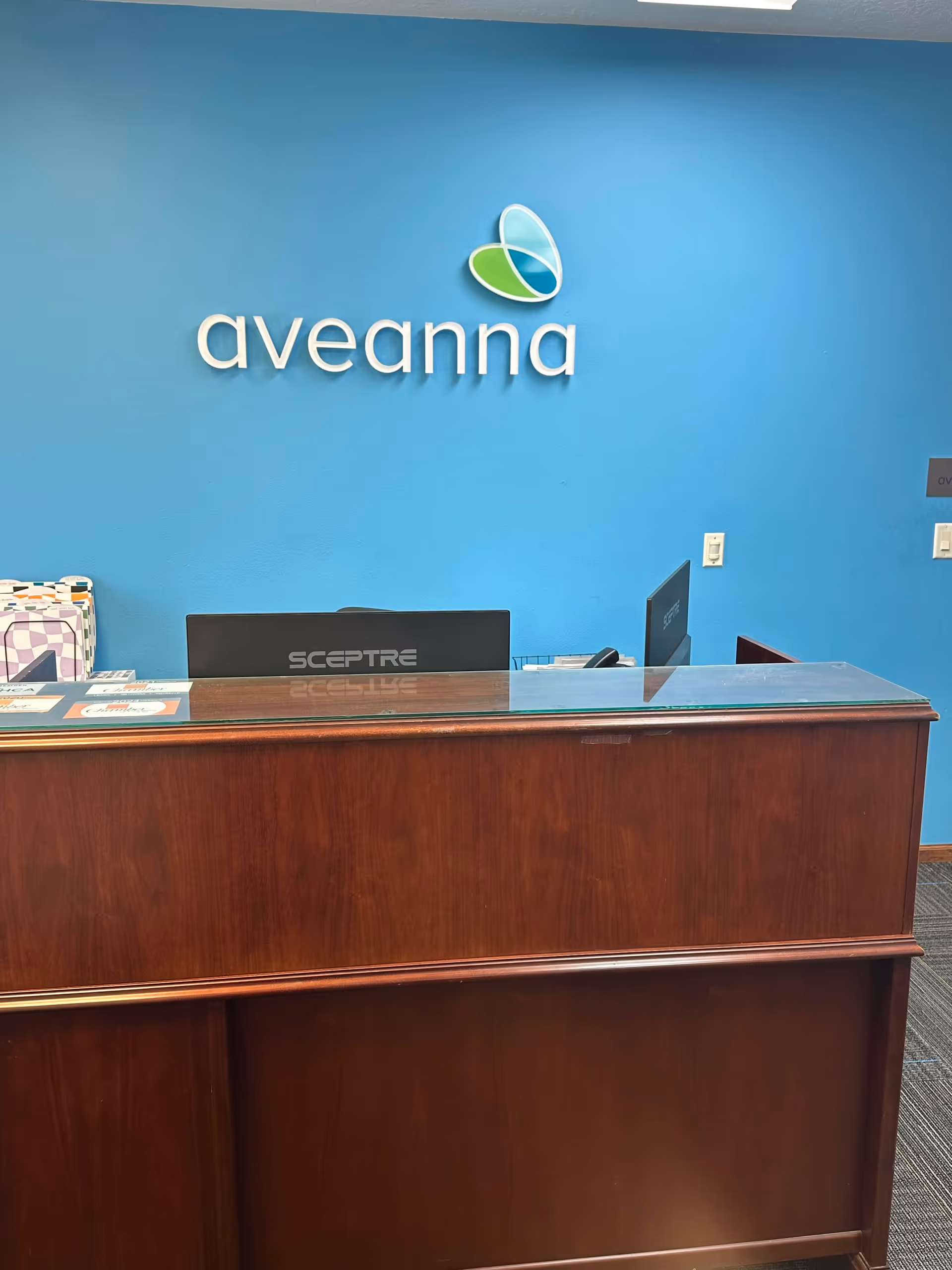Blue-walled reception area with Aveanna logo and wooden front desk.