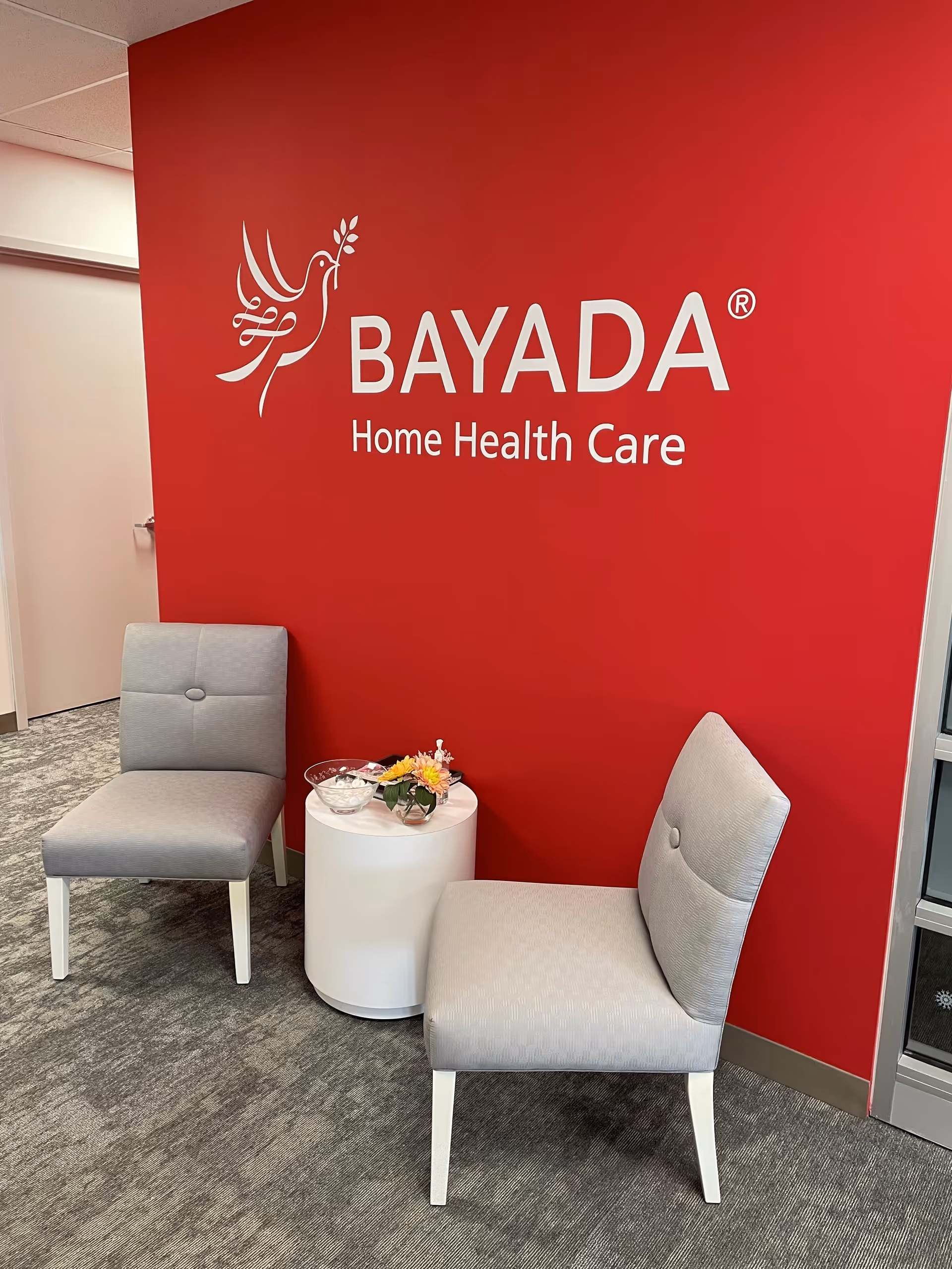 Indoor lounge with BAYADA logo on a red wall and chairs.