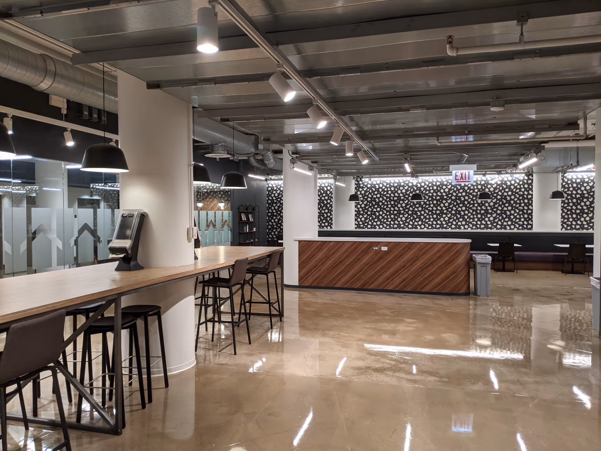 Modern facility common area with long wooden counter, bar stools, and central reception desk.