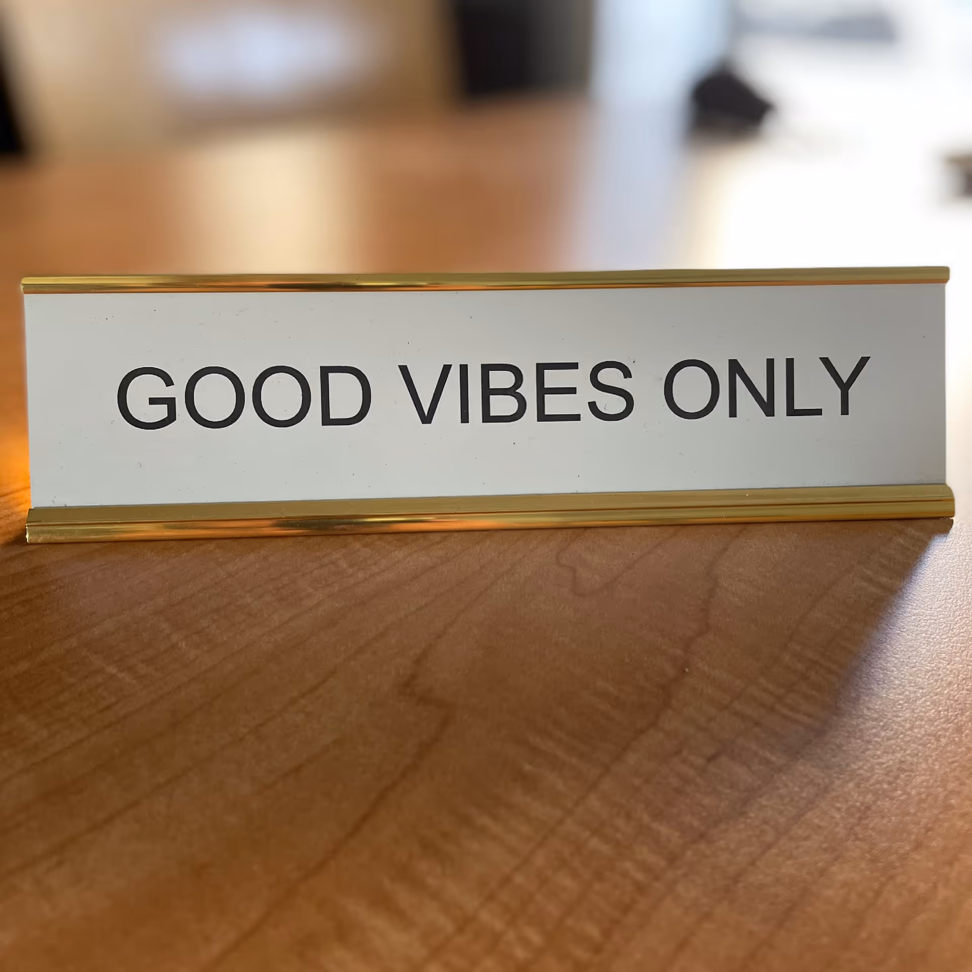 Close-up of a 'GOOD VIBES ONLY' sign on a wooden table indoors.