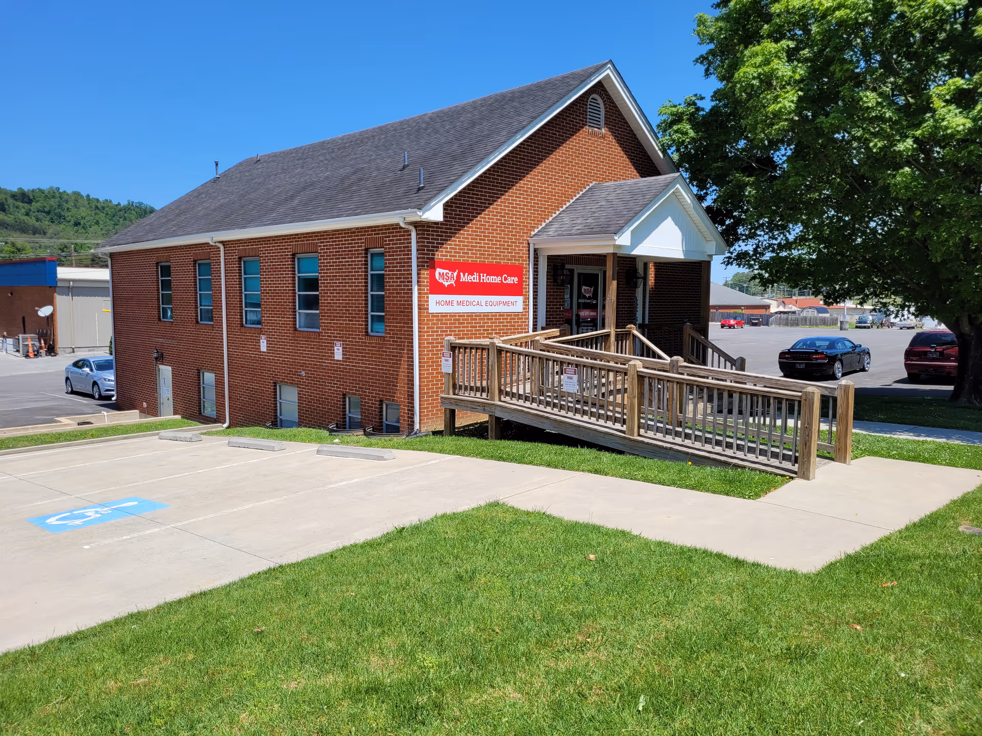 Exterior view of Medi Home Care building with ramp, parking, and green lawn.