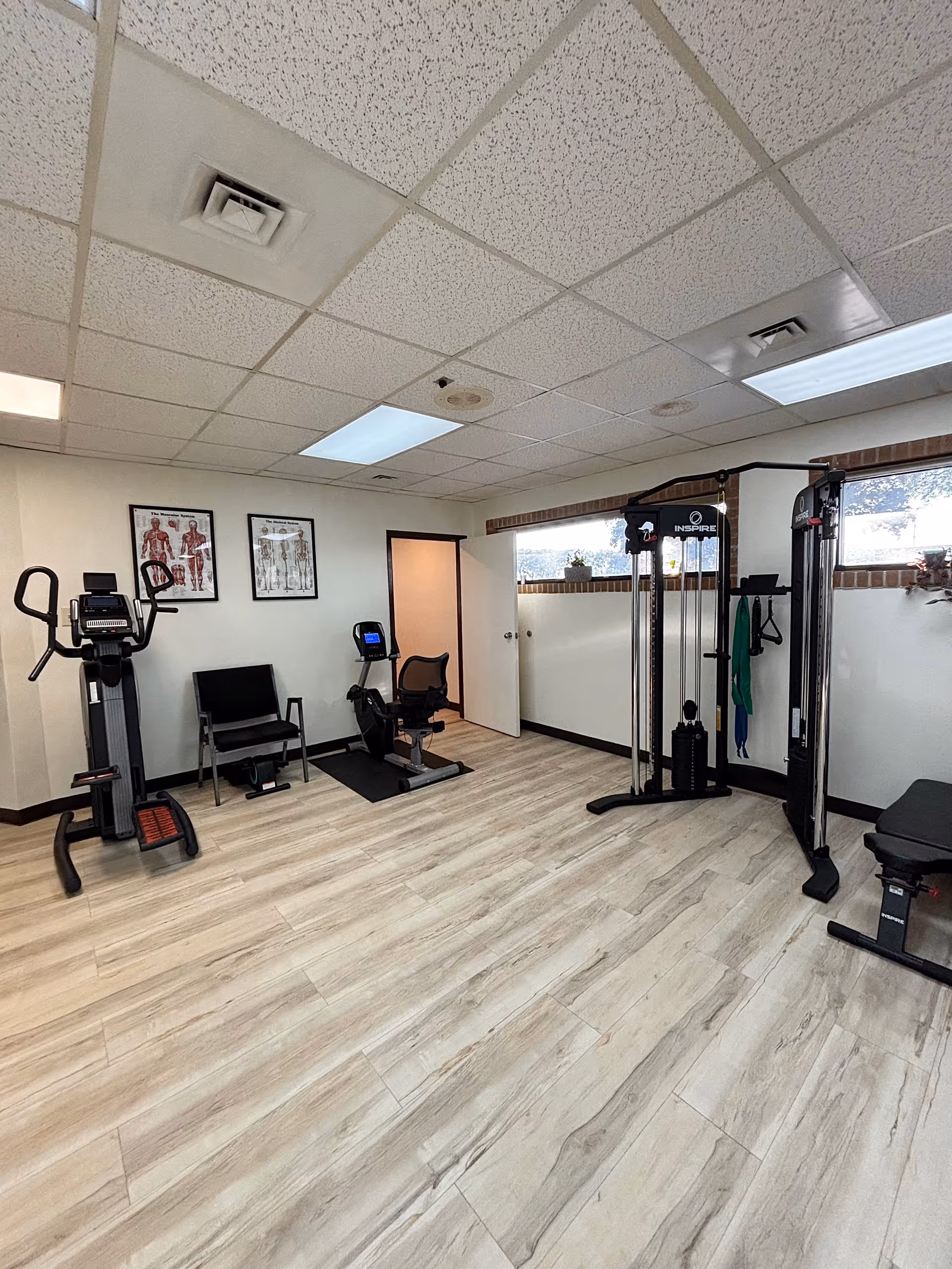 Empty Apex Physical Therapy Merrillville gym with cardio machines and weight equipment.