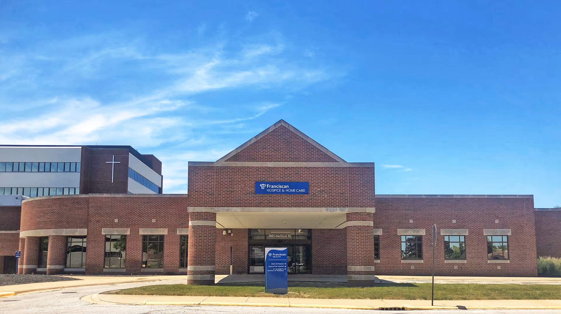 Brick senior care facility exterior with entrance and Franciscan Hospice sign