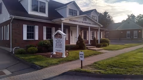 Brick building with a covered front entrance and sign.