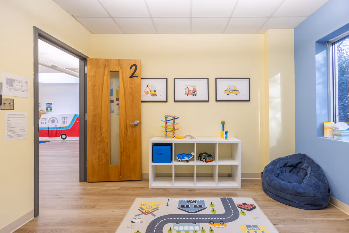 Interior playroom with toy shelves, bean bag chair, road rug, and a door marked 2.