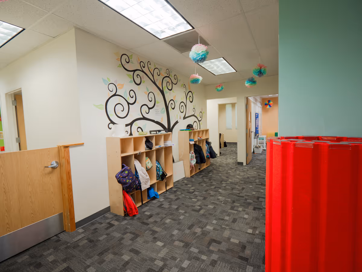 Hallway interior with cubbies, coats, and a decorative wall tree mural.