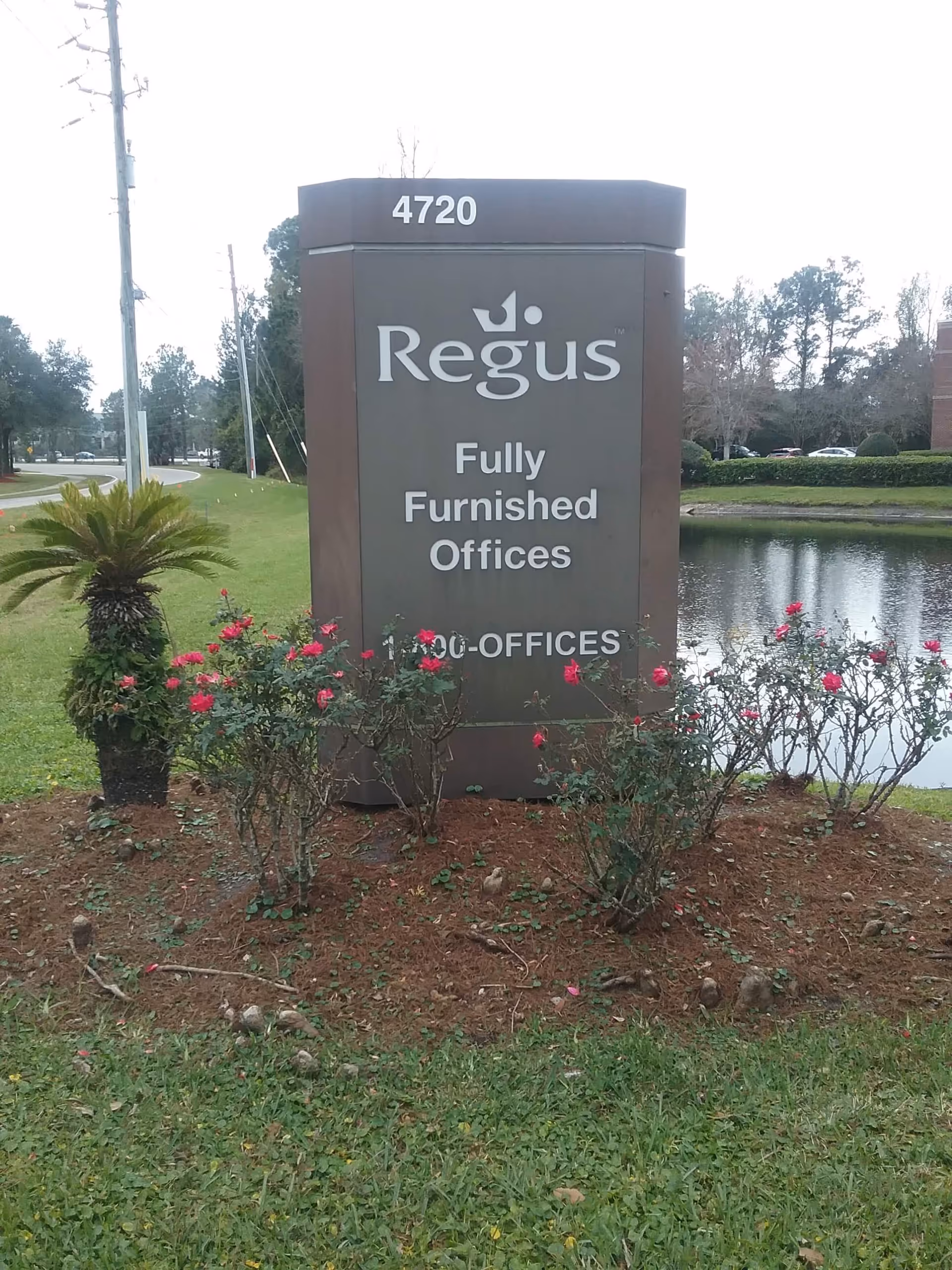 Outdoor sign for Regus Fully Furnished Offices, with rose bushes nearby.