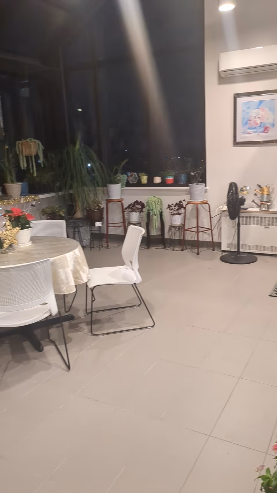 Indoor dining area with round tables, chairs, and potted plants along the windows.
