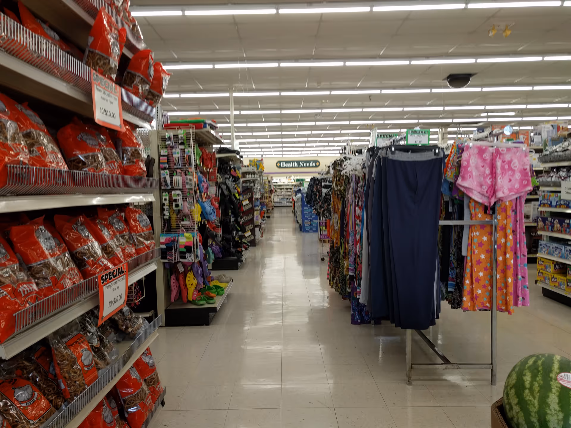 Narrow store aisle with shelves of groceries and clothing inside Discount Drug Mart.