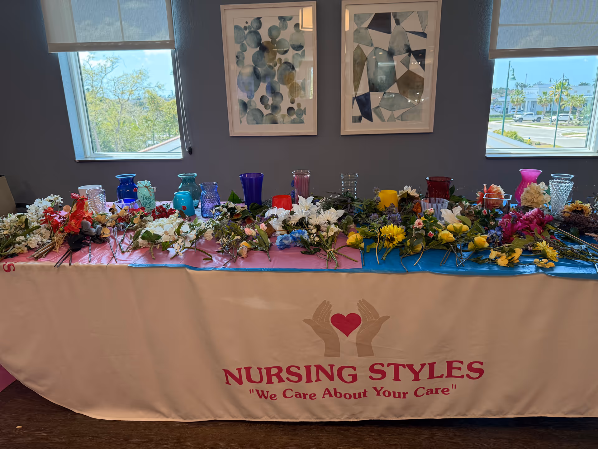 Long table with flowers and colorful glass vases indoors, Nursing Styles banner visible.