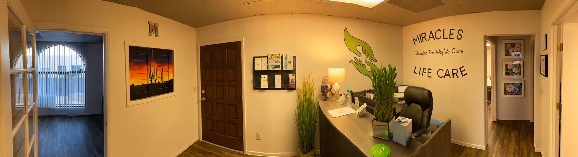 Reception area inside Miracles Life Care with front desk, plants, and wall signage.