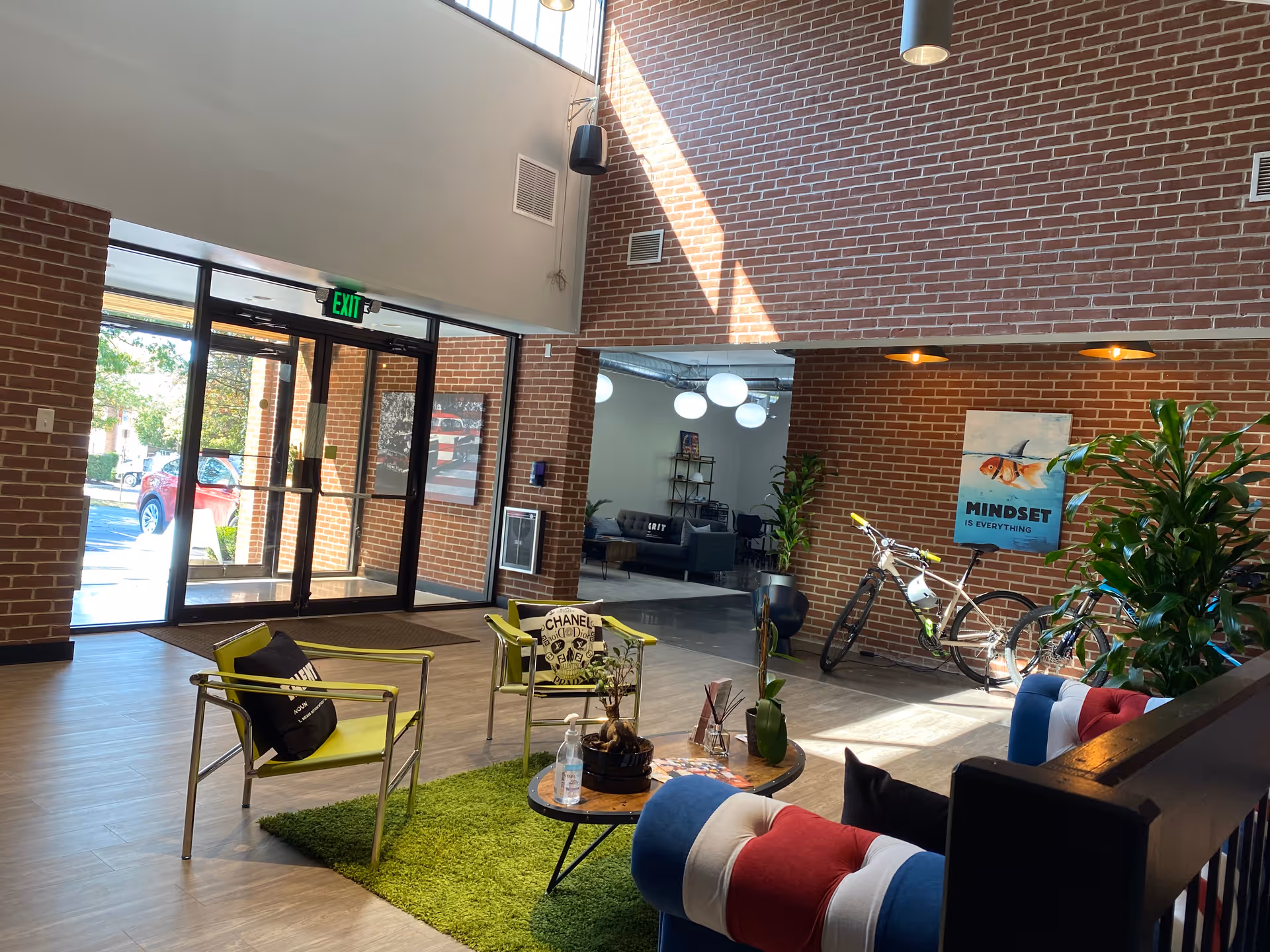 Lobby area inside brick building senior living facility with modern seating, plants, and a bike sculpture.