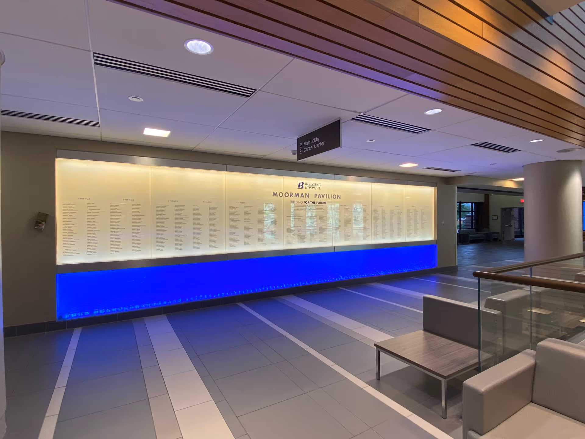 Bright hospital lobby with a long illuminated directory board and seating area.