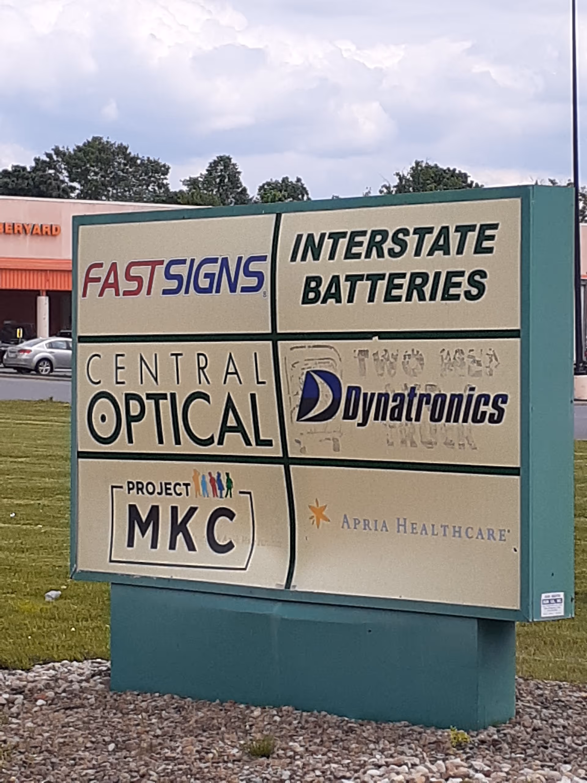 Outdoor signboard with multiple business logos, including Apria Healthcare and Interstate Batteries.