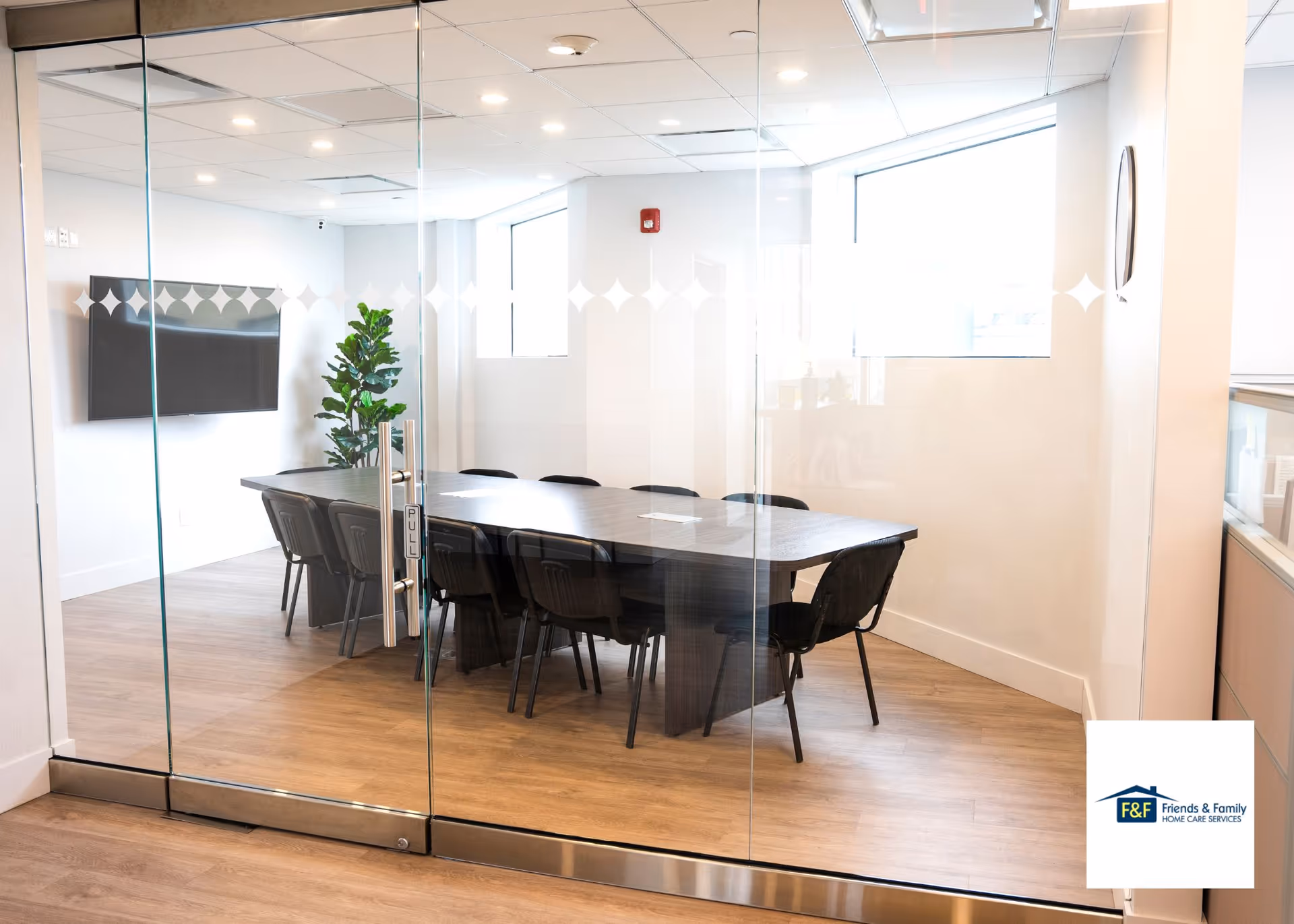 Glass-walled conference room with a long table and chairs inside a modern facility.