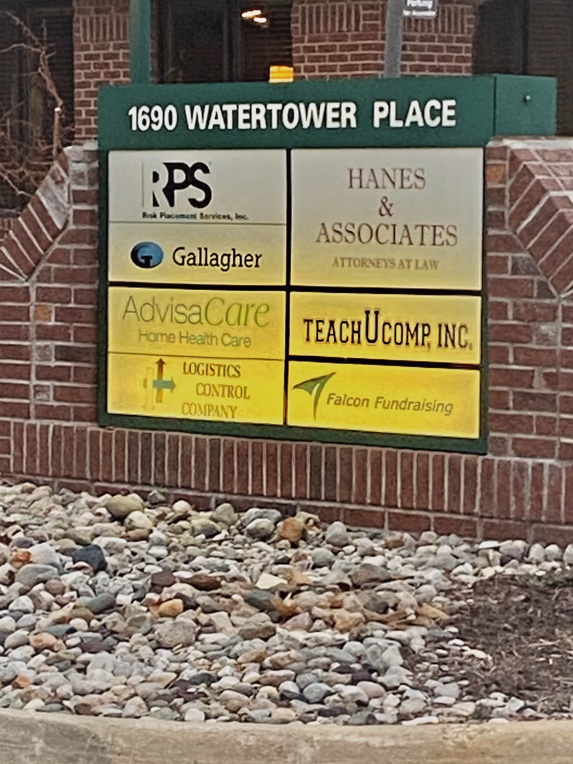 Signboard at brick front displaying multiple company logos and the address 1690 Watertower Place
