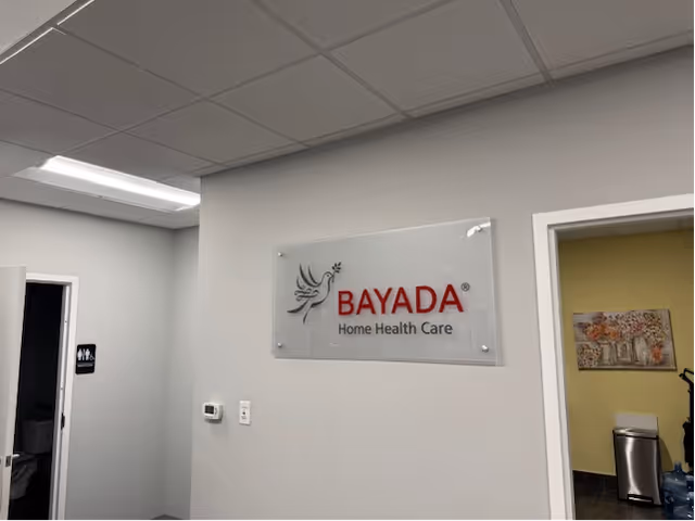 Interior hallway with BAYADA Home Health Care sign on gray wall and doorway to rooms.