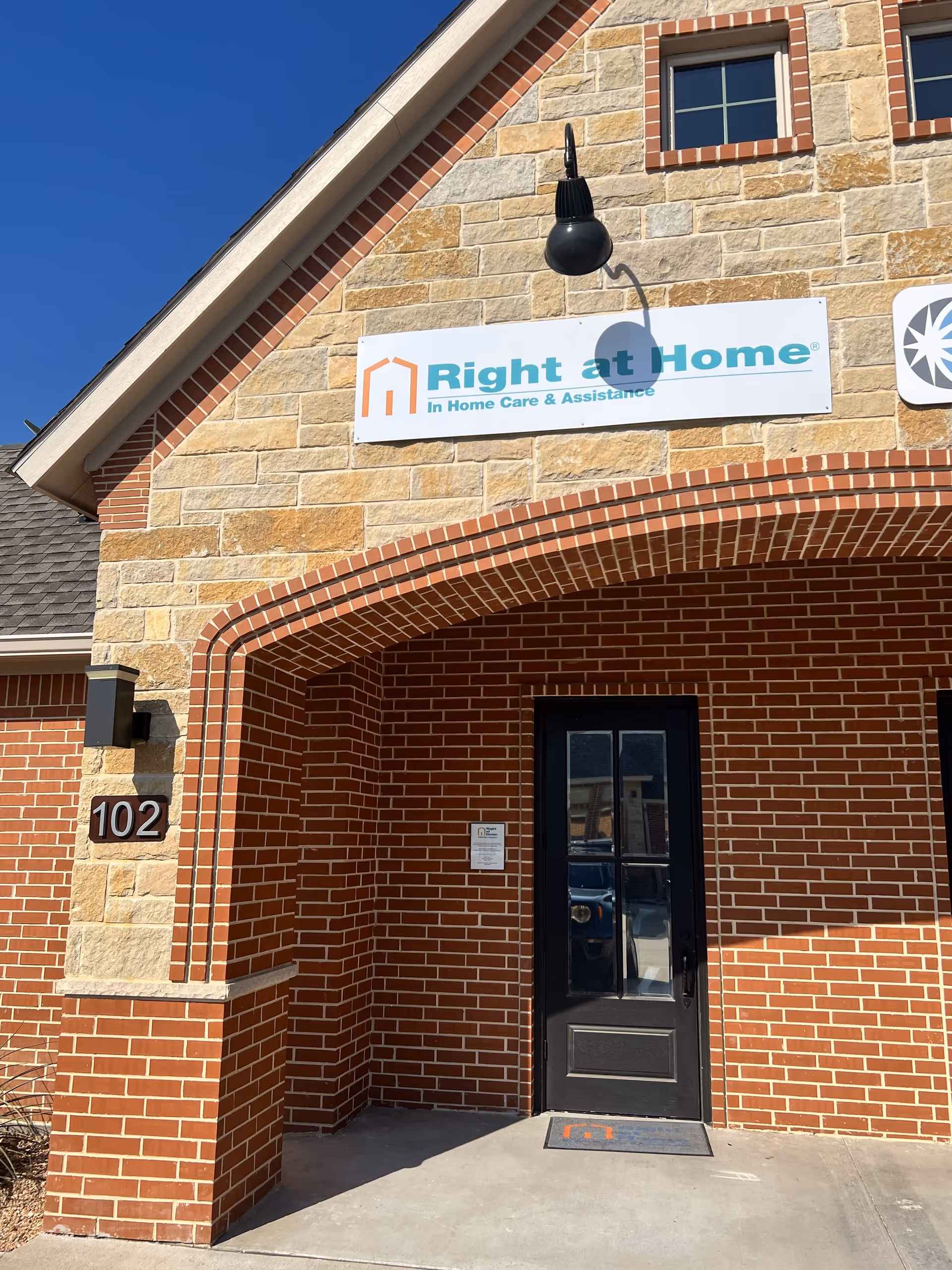 Exterior view of a Right at Home facility entrance on brick facade.