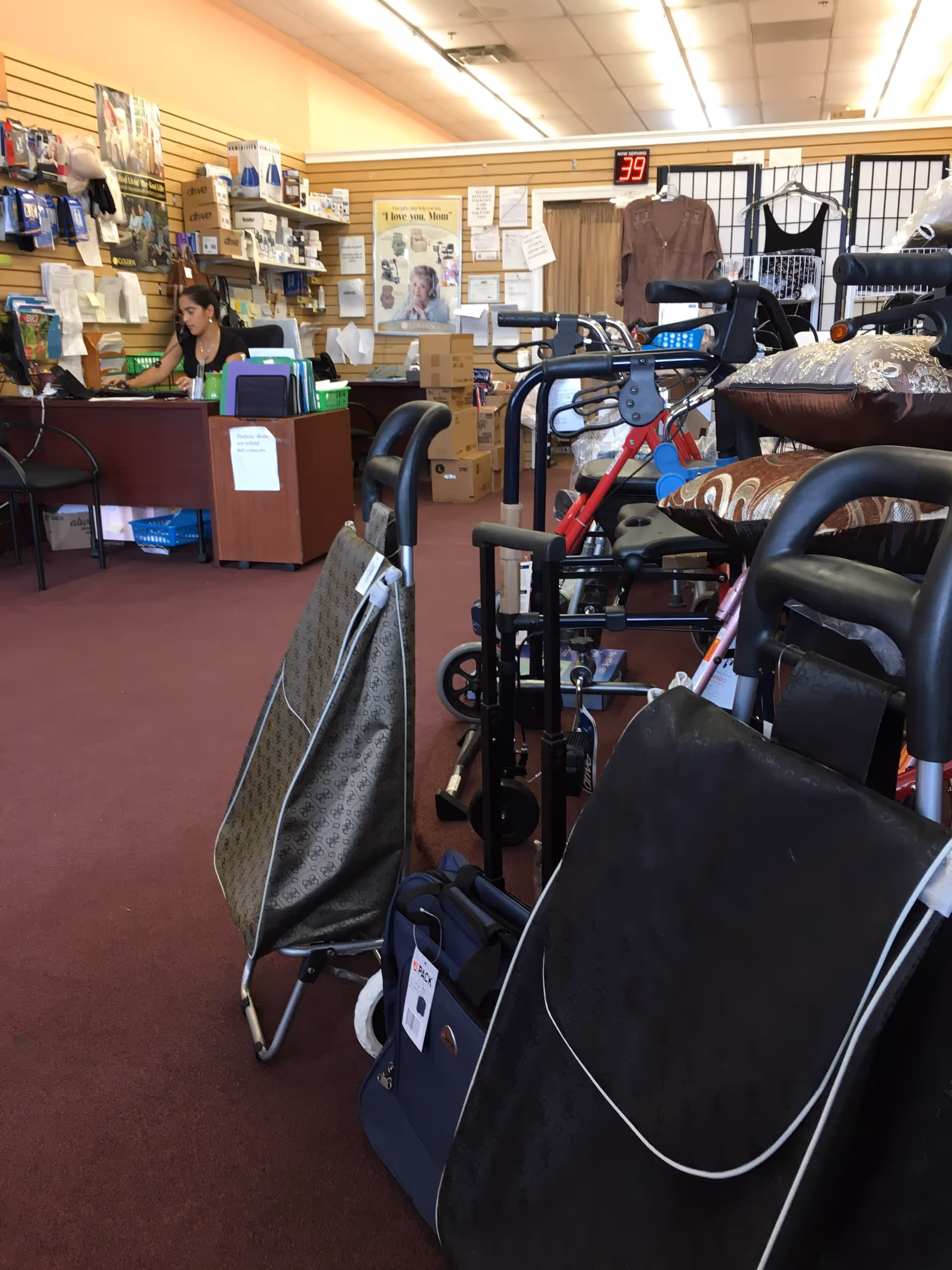 Interior of a senior facility equipment room with walkers, chairs, and a receptionist at a desk.