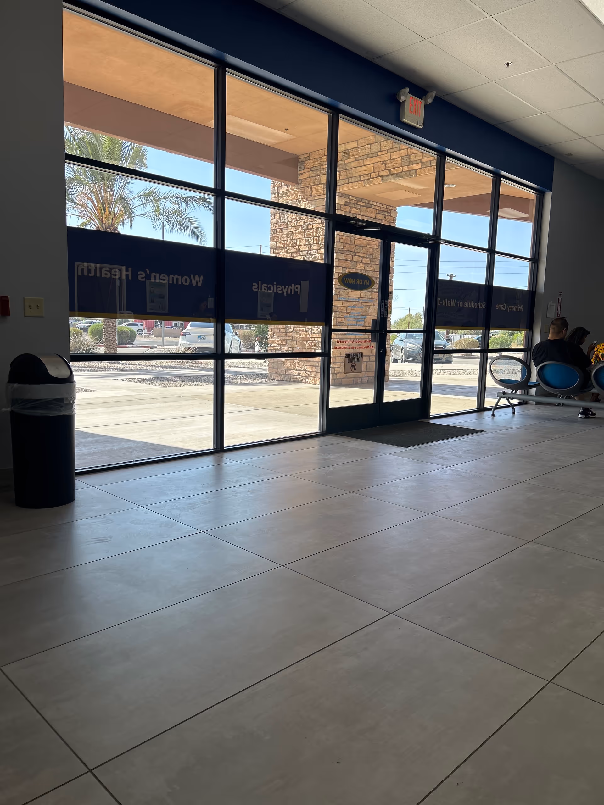 Inside a senior living facility lobby with glass doors, tiled floor, and seating area.