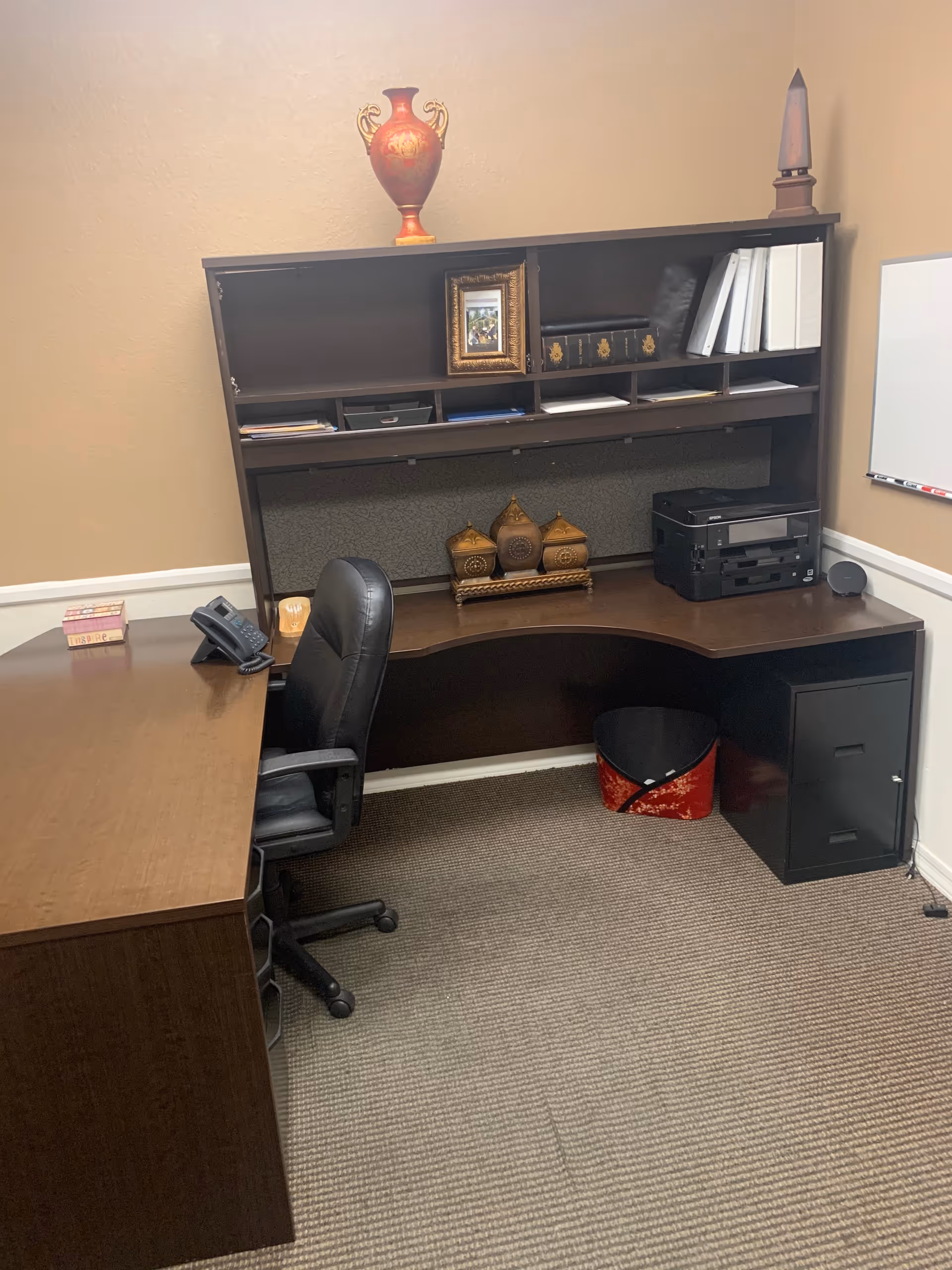 Office workspace in a senior care facility with a desk, chair, shelves, and printer.