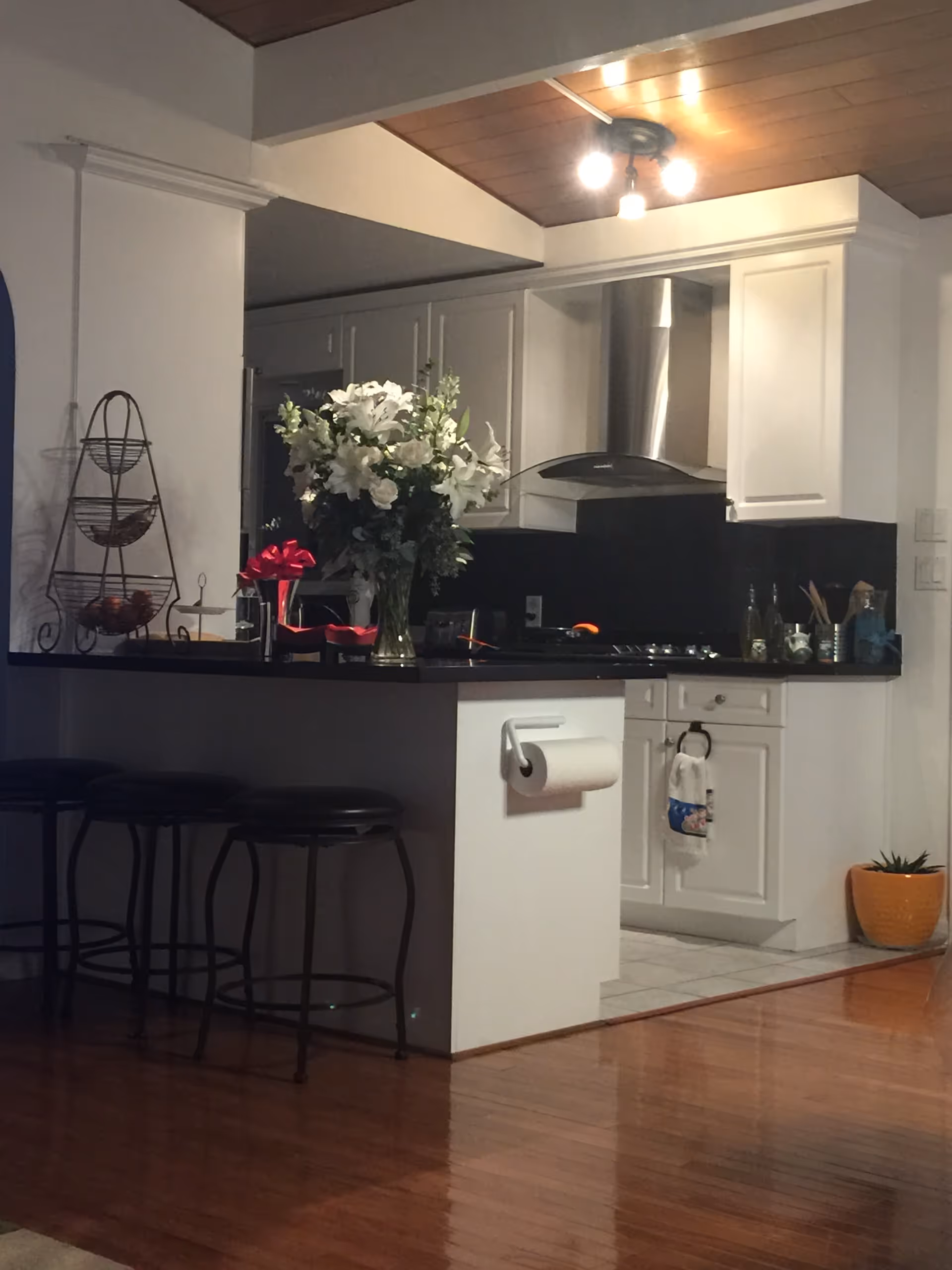 Open kitchen with white cabinets, black countertops, a bar with stools, and a flower bouquet.