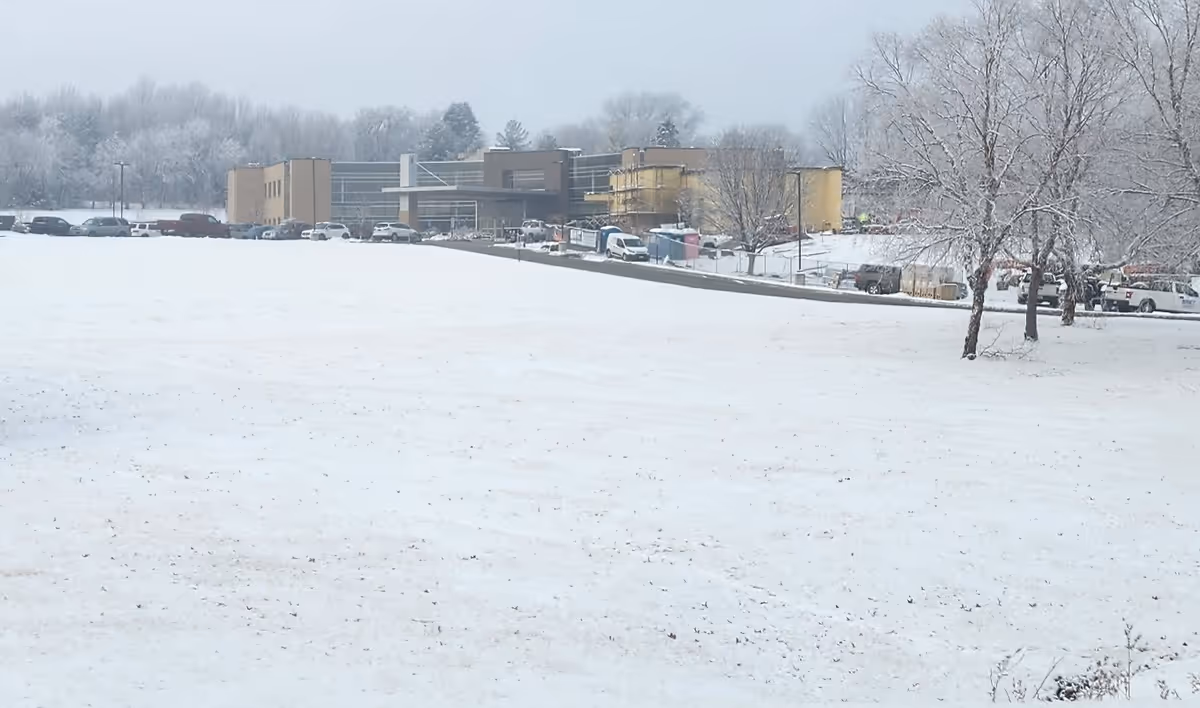 Snow covers a parking lot in front of Shenandoah Medical Center with bare trees.