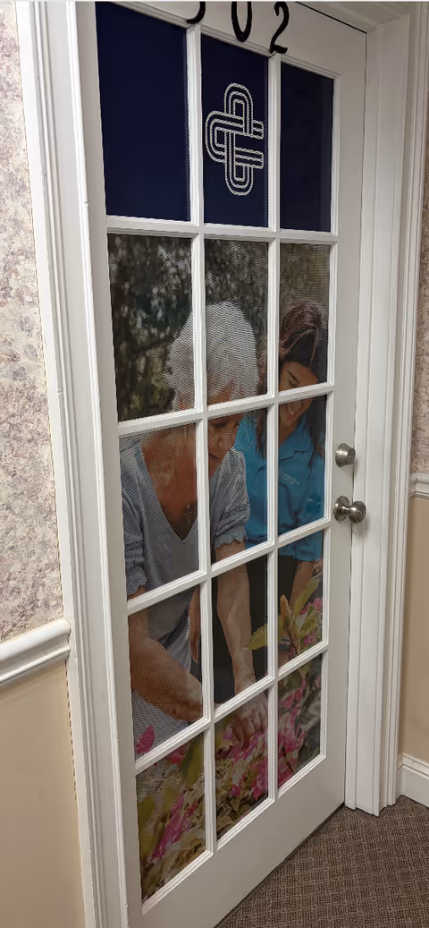 Door with grid panes reveals two people inside a Cornerstone Caregiving facility.