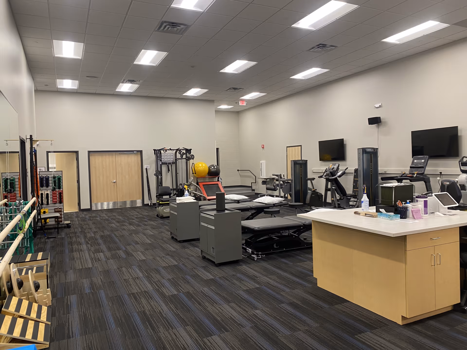 A spacious indoor gym with treadmills, weight machines, and a front desk.