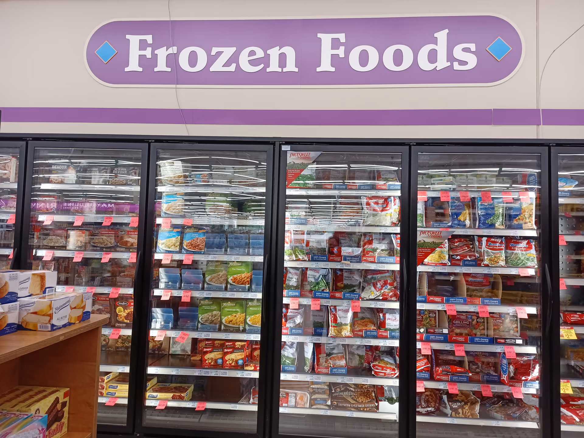 Inside a grocery freezer section labeled Frozen Foods with glass doors and stocked boxes.