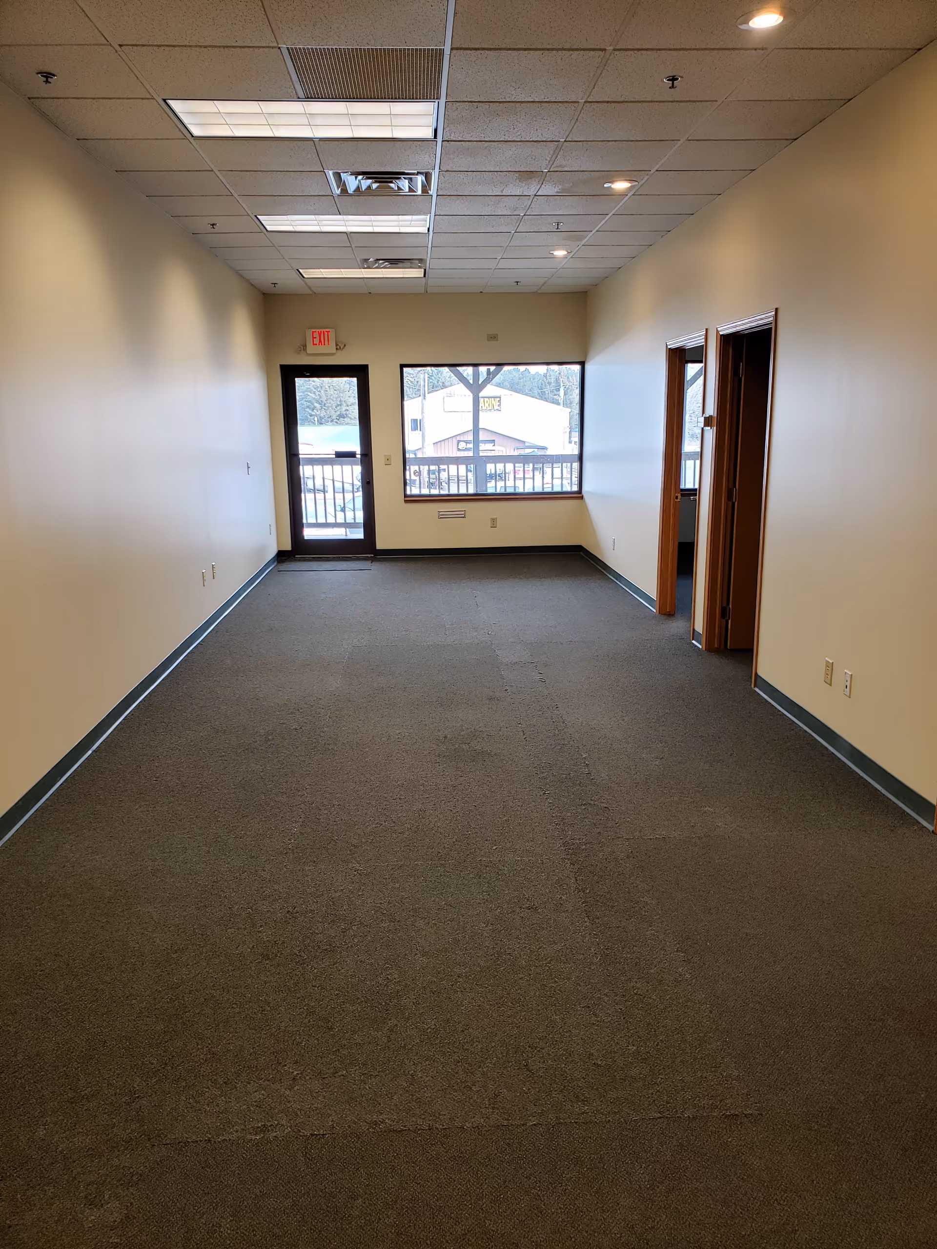 Interior corridor in a senior living facility with doors and a window at the end.
